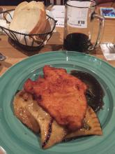 Chicken schnitzel with a side of pierogies, braised greens, onion gravy 